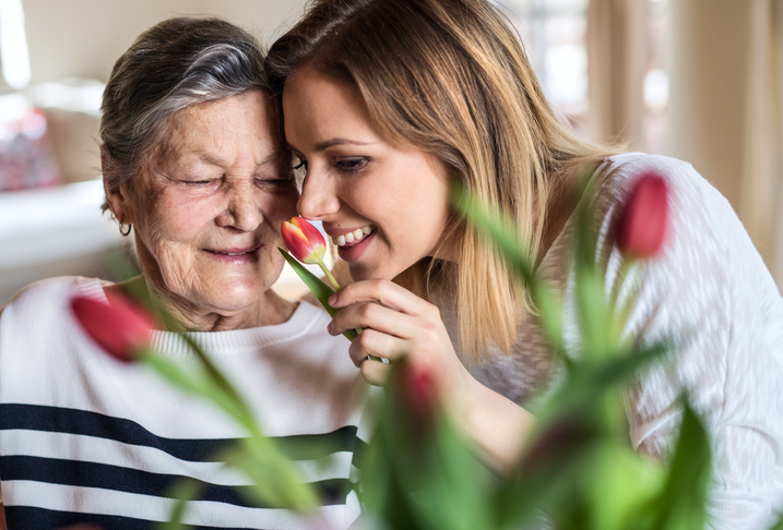older female adult with family member smiling and enjoying tulips