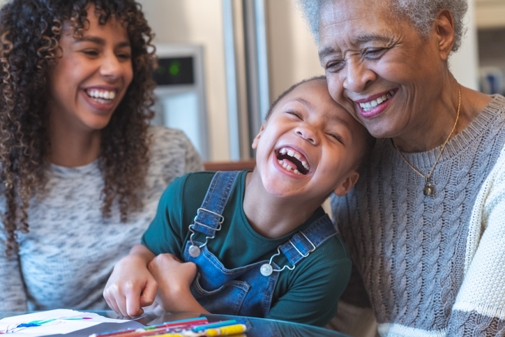 older lady with daughter and grandchild smiling and laughing