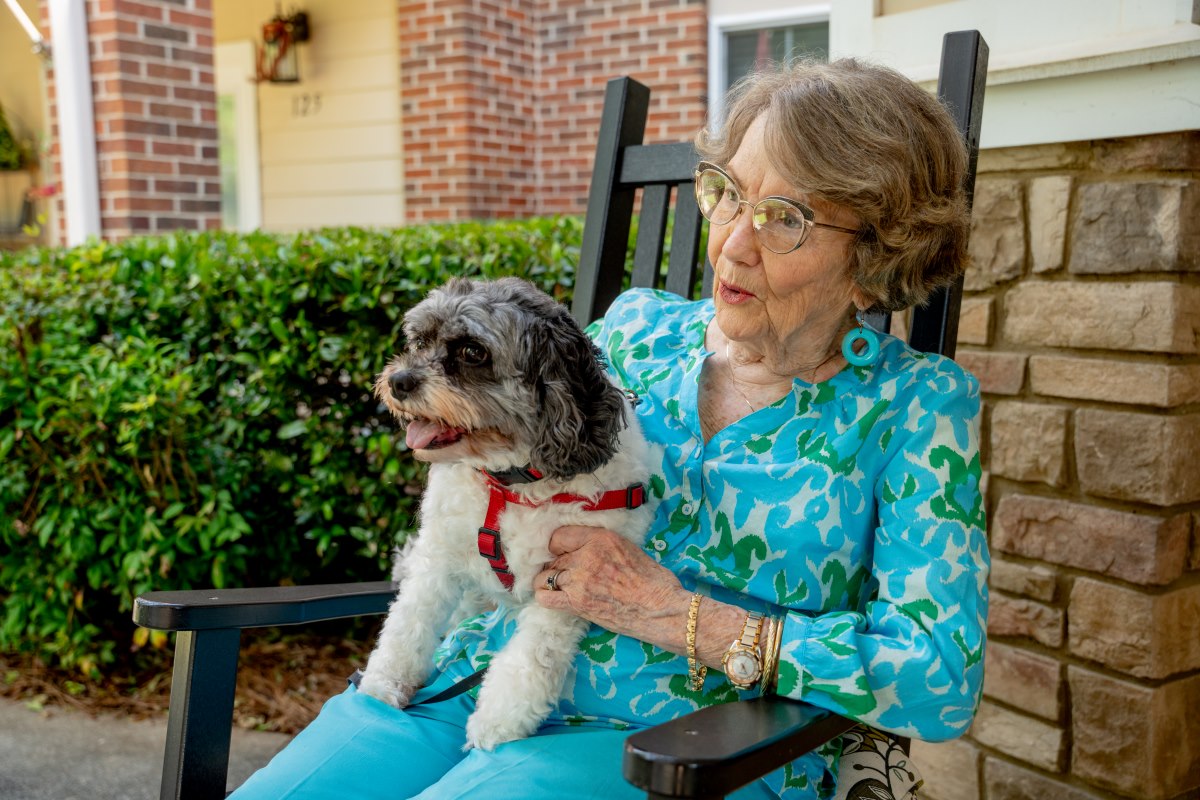 older adult sitting outside holding smiling dog