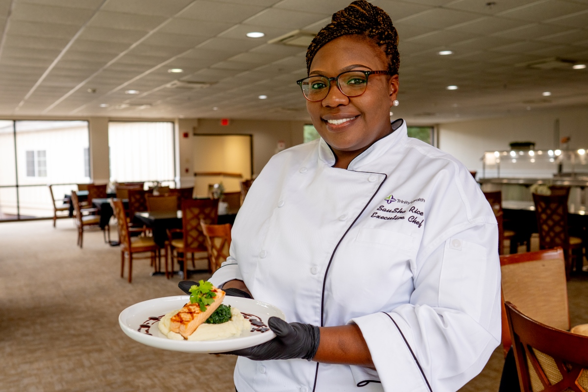 chef holding plated meal featuring salmon