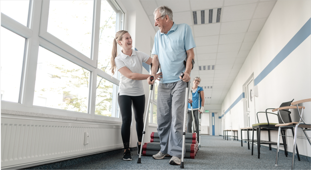 man walking with crutches next to a nurse