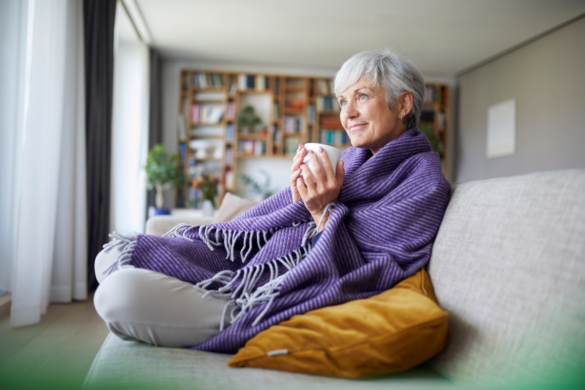 female older adult on couch sipping coffee