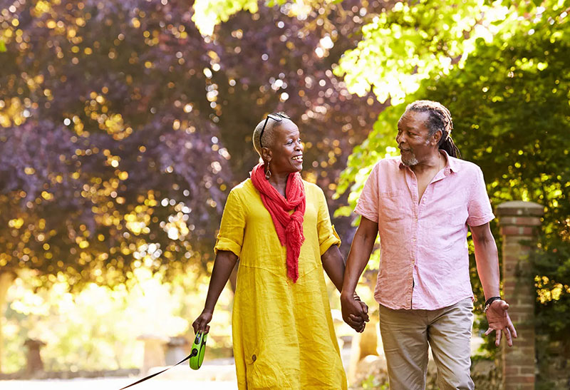 A couple holding hands walking in a wooded area