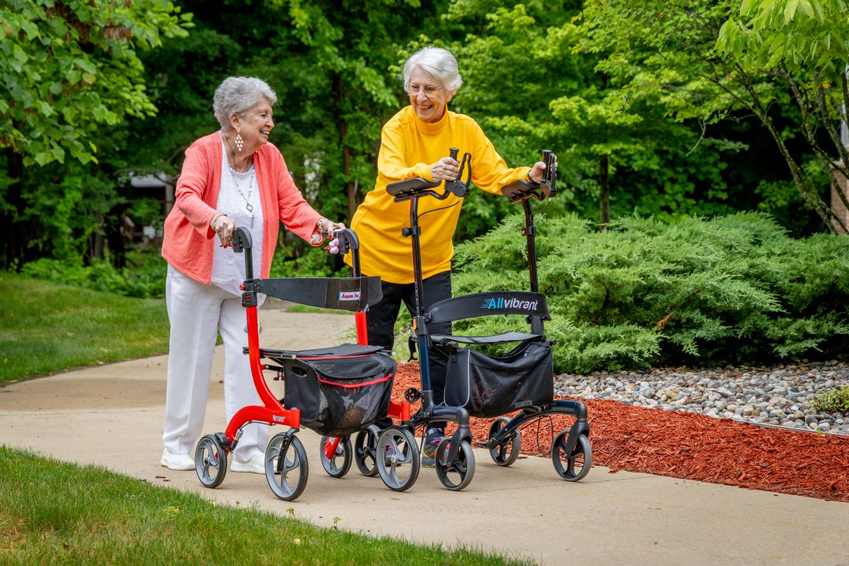 two ladies with walkers on the sidewalk enjoying a walk