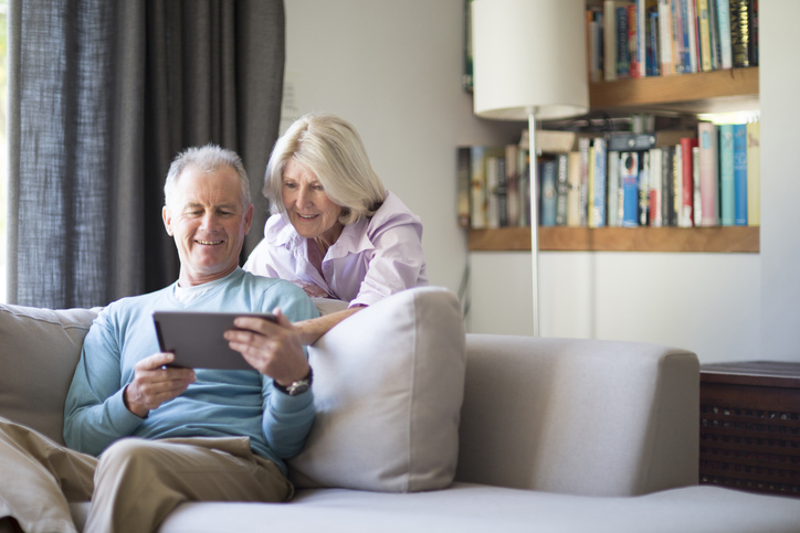 older couple in living room looking at tablet