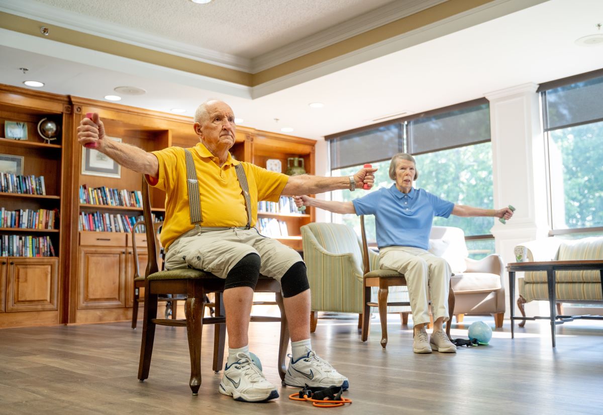 Two Assisted Living Residents in fitness class using arm weights